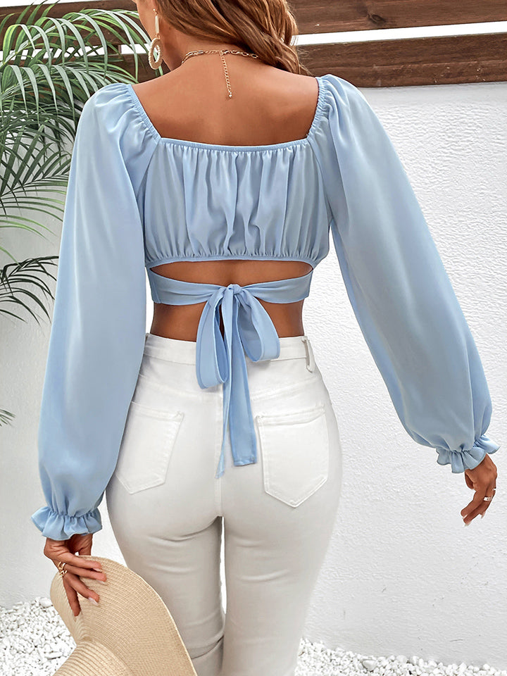 A woman poses in a light blue crop top with puff sleeves